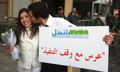Lebanese activists, playing the role of bride and groom, kiss as they hold a banner during a mock civil marriage ceremony - By Mohamed Azakir/REUTERS